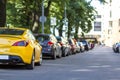 Long row of cars parking along a city road under shadow of big t Royalty Free Stock Photo