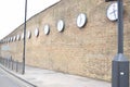 Long row of clocks on a high brick wall