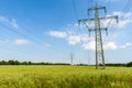 Long Row of High Voltage Electricity Pylons on a Green Meadow with Poppies Royalty Free Stock Photo