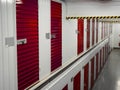 Long row of red color doors of self storage facility. Service to keep safe extra belongings. Nobody. Selective focus. Clean and Royalty Free Stock Photo