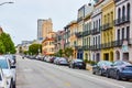 Long row of residential apartment buildings with unending street lined with cars