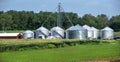 Long rows of corn and soybean in farm field, crop storage silos, red barn