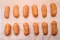 Long rows Eclair shells. Eclairs candy paper. The process of making cakes.