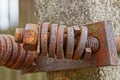 Long rusty brown bolt with many washers and a nut