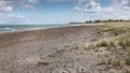 Long sandy beach with grass on the right. the sea is seen on the left. houses, cliff green and yellow in the background. Gerrild Royalty Free Stock Photo