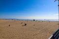 A long sandy beach with people relaxing on the beach with a gorgeous clear blue sky at Santa Monica Beach