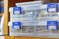 Long self-tapping screws in transparent plastic storage box on the shelf in workshop Royalty Free Stock Photo