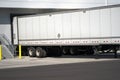 Long semi trailer loading industrial cargo in warehouse dock wit