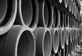 Long series of stacked reinforced concrete pipes in black and white