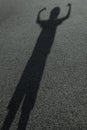 Long shadow of a kid raising hands in the street