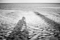 Long shadow of the man taking photo of himself on a sand beach with blurred sea in background,sad concept,lonely concept