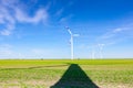 Long shadow under windmill, large wind power turbines spinning to generating clean, green, renewable energy Royalty Free Stock Photo