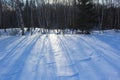 Long shadows from the late afternoon sun cast on the spotless snow in wintertime.