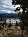 Long shadows,trees, and clouds over snow capped mountain peaks. Royalty Free Stock Photo