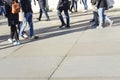 Long shadows of walkers walking on bright concrete slab paving