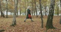 Long shot. Caucasian blond woman slomo walking through fall woods.Following side gimbal.Storytelling real young adult