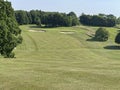 Uphillgolf hole with a green, a bunker and trees Royalty Free Stock Photo