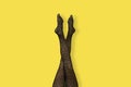 Long slender Legs of young woman in black tiger print tights on yellow background Royalty Free Stock Photo