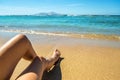 Long slim young woman legs relaxing lying down and sunbathing on sand tropical beach under hot sun in summer. Skincare, sun aging Royalty Free Stock Photo