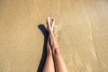 Long slim young woman legs relaxing lying down and sunbathing on sand tropical beach under hot sun in summer. Skincare, sun aging Royalty Free Stock Photo