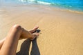 Long slim young woman legs relaxing lying down and sunbathing on sand tropical beach under hot sun in summer. Skincare, sun aging Royalty Free Stock Photo