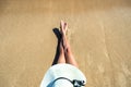 Long slim young woman legs relaxing lying down and sunbathing on sand tropical beach under hot sun in summer. Skincare, sun aging Royalty Free Stock Photo