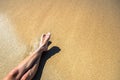 Long slim young woman legs relaxing lying down and sunbathing on sand tropical beach under hot sun in summer. Skincare, sun aging Royalty Free Stock Photo