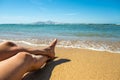 Long slim young woman legs relaxing lying down and sunbathing on sand tropical beach under hot sun in summer. Skincare, sun aging Royalty Free Stock Photo