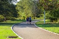 A long smooth winding footpath in the park with a man and woman walking along the path surrounded by gorgeous green grass