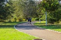 A long smooth winding footpath in the park with a man and woman walking along the path surrounded by gorgeous green grass Royalty Free Stock Photo