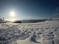 Long snowy field with footprints with beautiful bay, blue fjord and sky on a sunny winter day Royalty Free Stock Photo