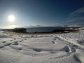 Long snowy field with footprints with beautiful bay, blue fjord and sky on a sunny winter day Royalty Free Stock Photo