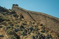 Long solid wall made of stone rising along the hill