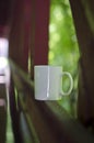 A long solo blank white coffee mug along a bridge.