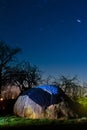 Long star tracks in clear deep blue night sky, beautiful countryside landscape with a haycock in a farm garden Royalty Free Stock Photo