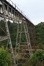 A very tall steel rail bridge over a deep, tree lined valley