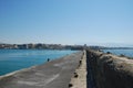 Long stone pier stretching into the blue sea