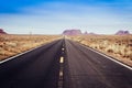 Long straight american road with vanishing point into Monument Valley