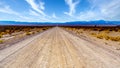 A long and straight gravel road in the semi desert landscape near Crystal Springs and Area 51 in the desolate land of Nevada Royalty Free Stock Photo