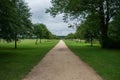 Long straight gravel/sand path surrounded by green trees