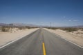 Long straight road through barren desert landscape of California