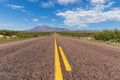 Long straight road in the desert, leading to a beautiful mountain range under a blue sky Royalty Free Stock Photo