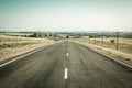 Long straight road with fields, forests and bushes on roadside. Beautiful horizon line with low mountains. Royalty Free Stock Photo