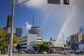 A long street lined with parked cars, office buildings, apartments, lush green palm trees and shops and cars driving with blue sky Royalty Free Stock Photo