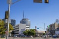 A long street lined with parked cars, office buildings, apartments, lush green palm trees and shops and cars driving Royalty Free Stock Photo