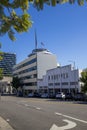 A long street lined with parked cars, office buildings, apartments, lush green palm trees and shops and cars driving Royalty Free Stock Photo