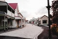 long street with stone paving in nice cozy quiet lonely town with wooden houses and buildings under cloudy sky, west