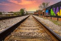 A long stretch of metal and wooden railroad tracks surrounded by gravel, red brick buildings and lush green trees Royalty Free Stock Photo