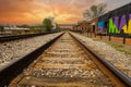 A long stretch of metal and wooden railroad tracks surrounded by gravel, red brick buildings and lush green trees Royalty Free Stock Photo