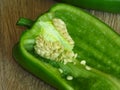 Long sweet green pepper cut in half on rustic style wood background. Pepper seeds. Royalty Free Stock Photo